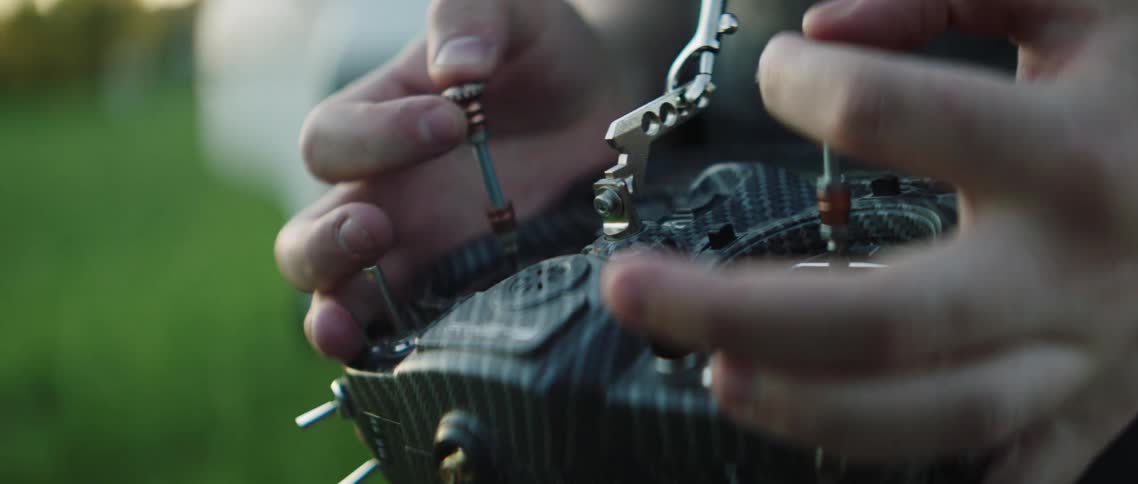 Hands controlling a drone controller outdoors on a lawn