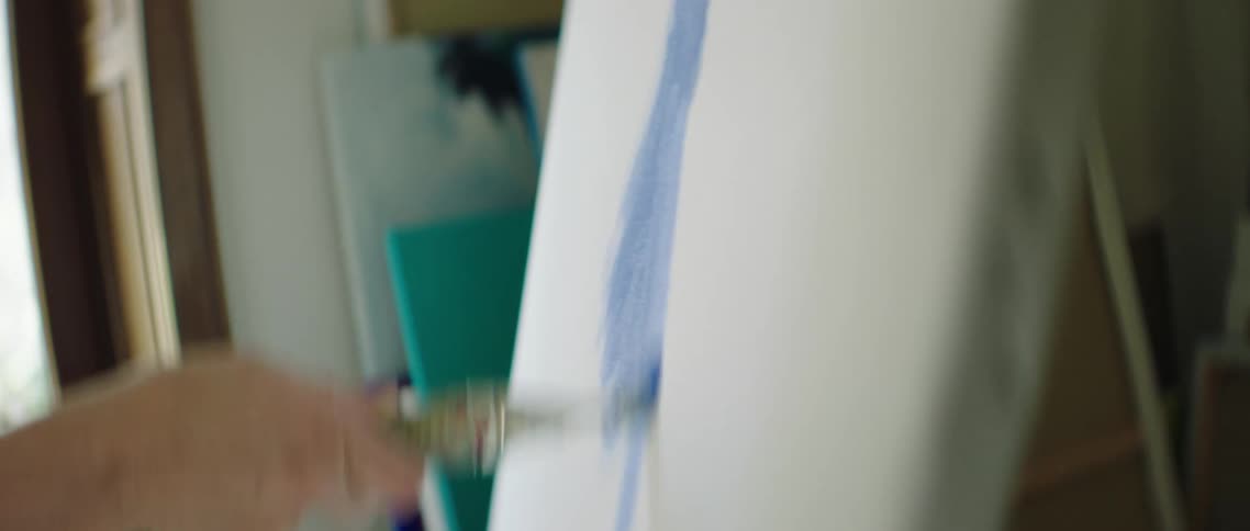 A white woman paints on a white canvas