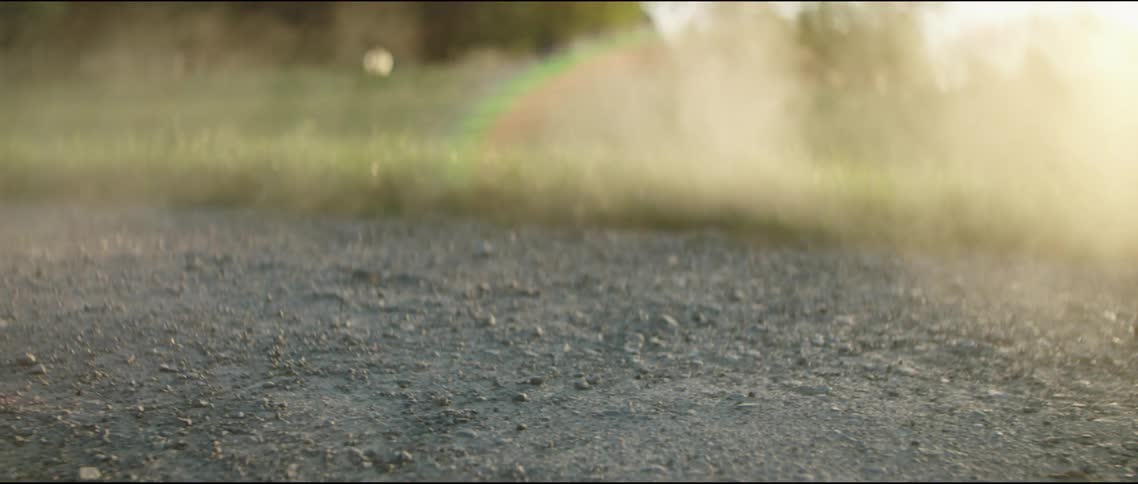 Drone stirs up cloud of dust flying off from dirt road