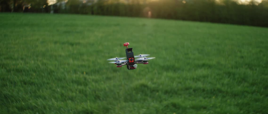 Small drone in flight over field