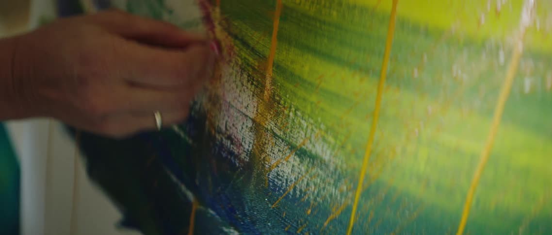 Womans hand coloring with oil pastel on painted canvas