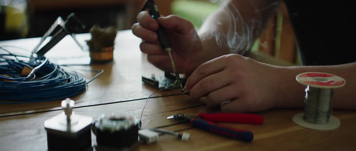 A person using a soldering iron on an electrical component