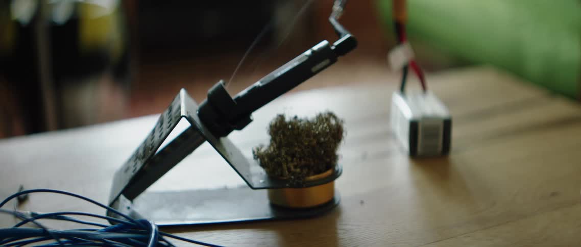 Person places soldering iron on metal stand