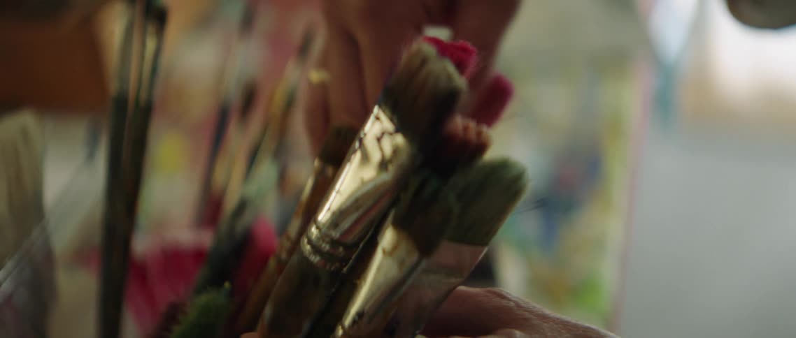 A woman goes through a container of used paint brushes and picks one