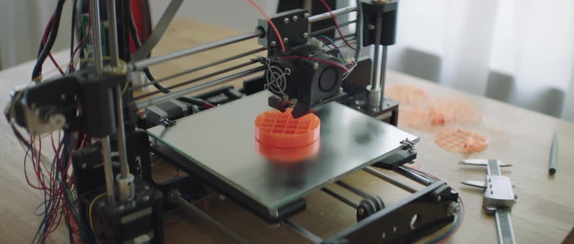 A machine moves around an orange disc on a metal plate