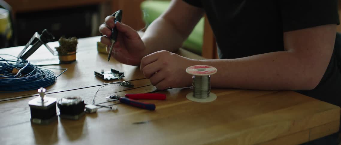 Man sitting at the table repairs an electronic device