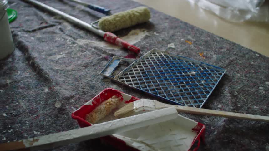 A wet paint stir stick is set down on a paint pan