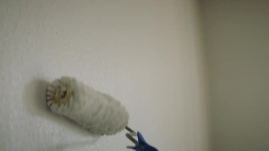 A white person paints a room with a paint roller
