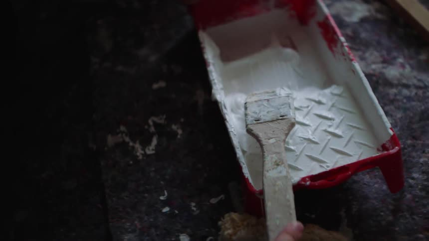 A person trying to clean off white paint on a paintbrush