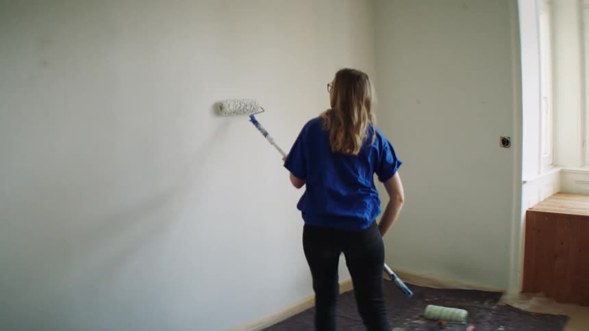 A woman painting a wall with a paint roller