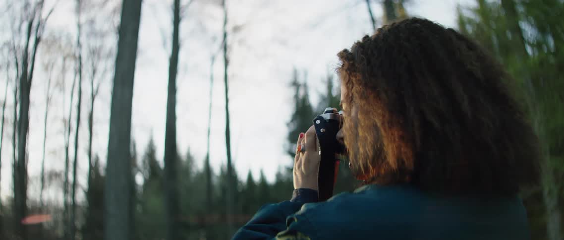 Woman takes a picture of the sunset in the forest