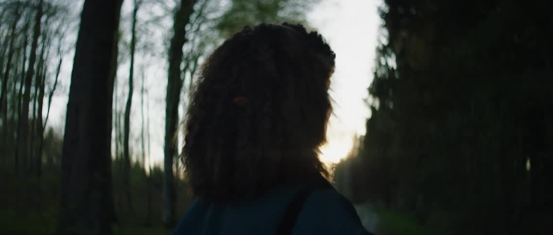A woman hikes down the trail listening to music on her headphones