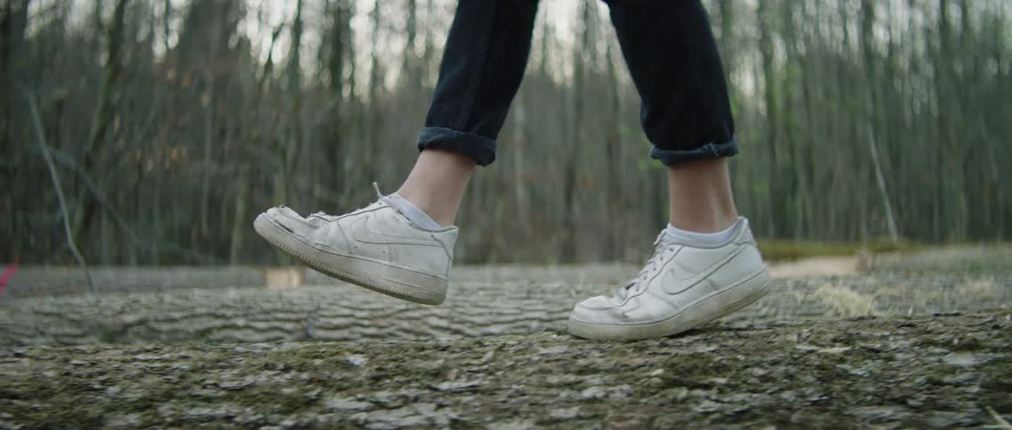 A person is walking over logs in the forest