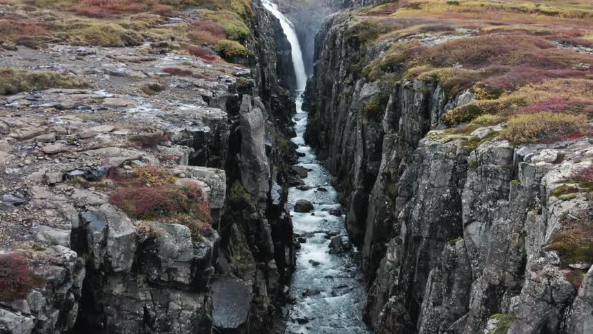 Waterfall flows down the side of a cliff in a canyon