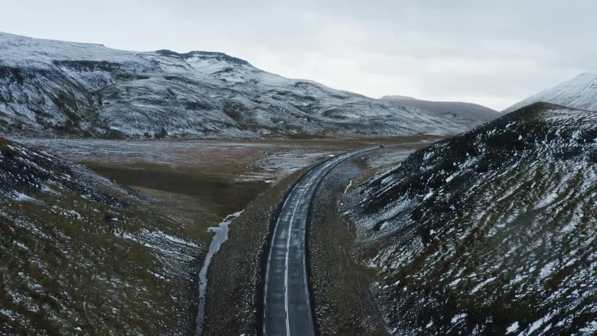 Vehicles drive down a road running through a mountain valley