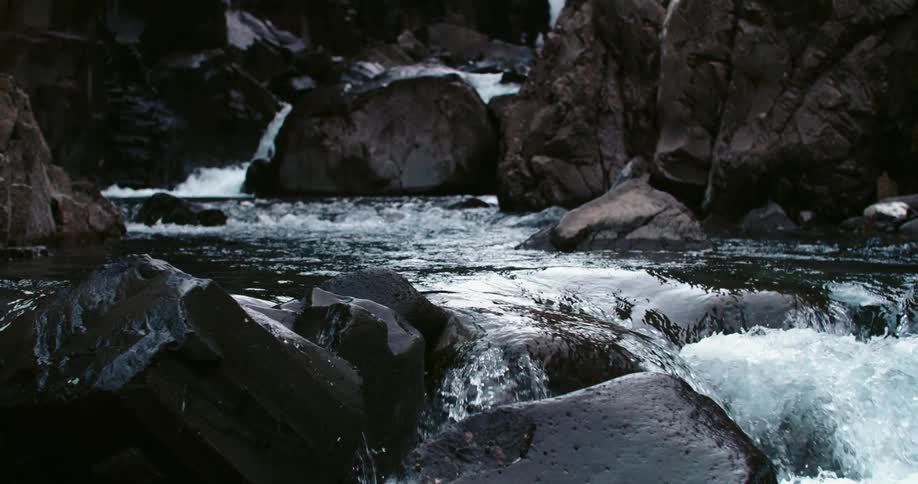 Water from a waterfall forms river flowing over rocks