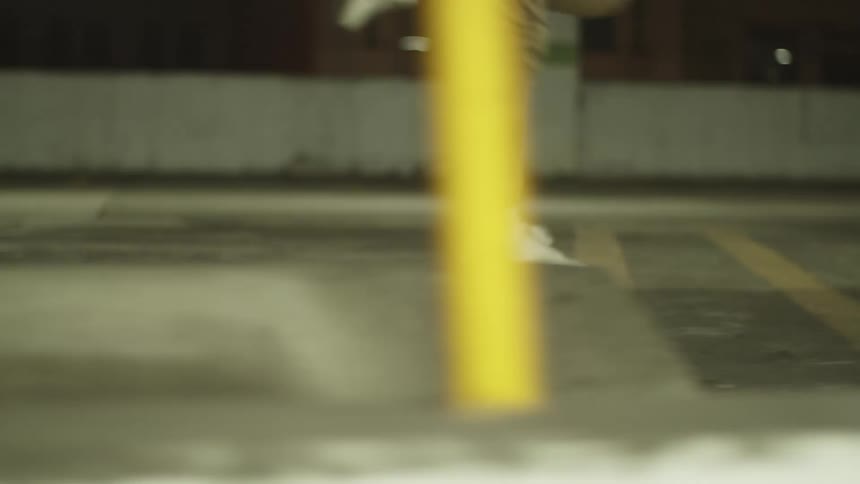 Person skips and dances through parking lot at night