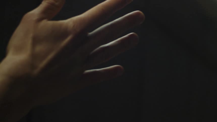 A mans hand and fingers undulate in the air as if playing music