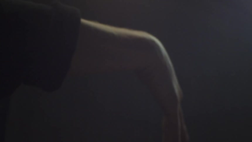 Hand stretching and twisting slowly under light in dark room