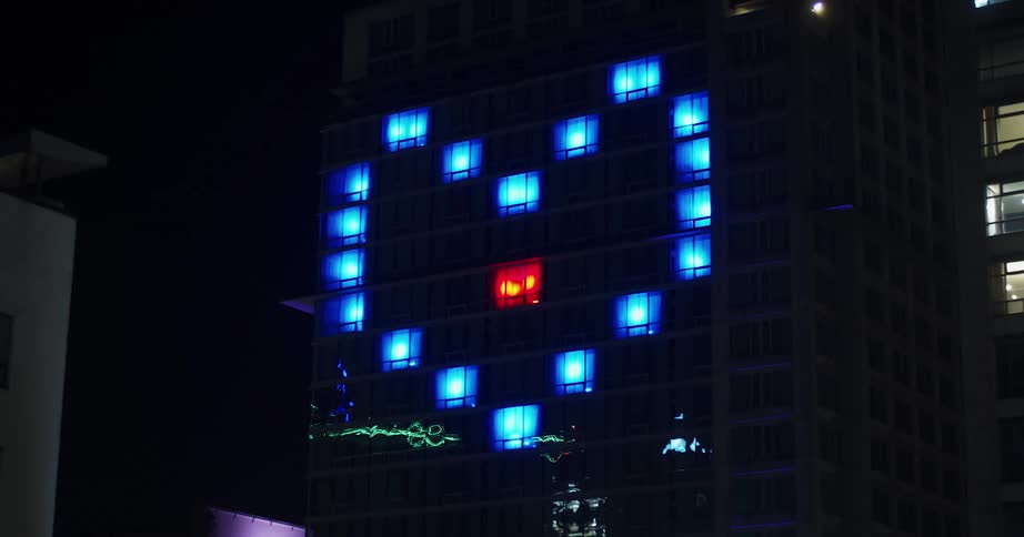 Windows in building used to create blue heart shape with red heartbeat at night