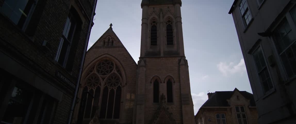 The tower of a cathedral looming high over the town causing the pathways below to be covered in shadow