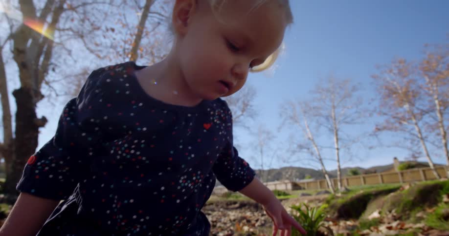 Young girl in pig tails walks on the rocks in a creek under the bright sun