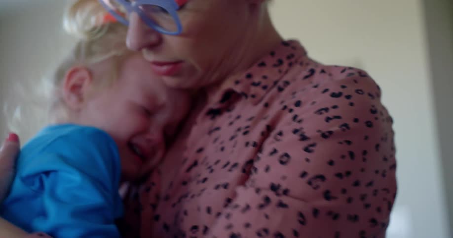 A mom holds her crying daughter and rubs her back to comfort her