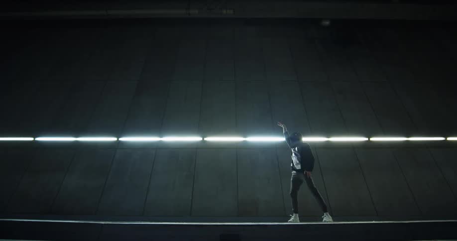 Dancer performs dance moves in front of a line of lights