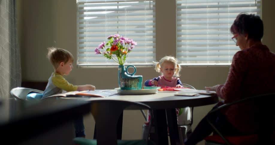 A woman sits down at a table with two small children