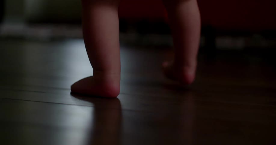 Baby takes first steps in the wooden floor of the living room