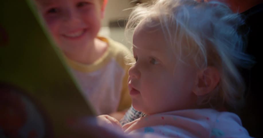 Mother reads to children in lap