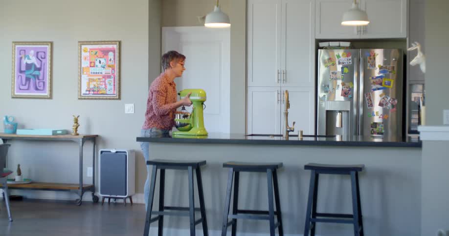 Woman carries a mixer to the kitchen counter top