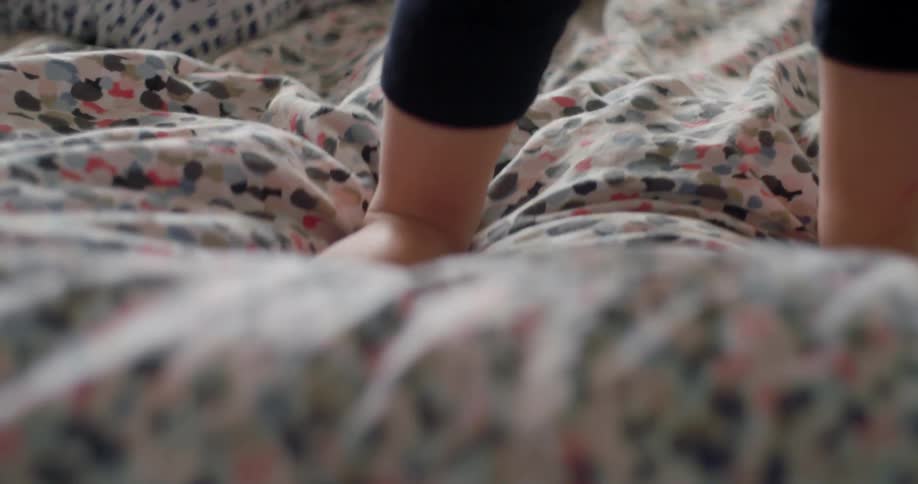 A bare foot child walks on a soft cushion and falls