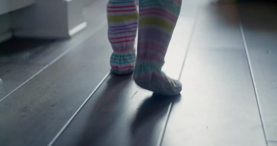 A toddler walks over a wooden floor