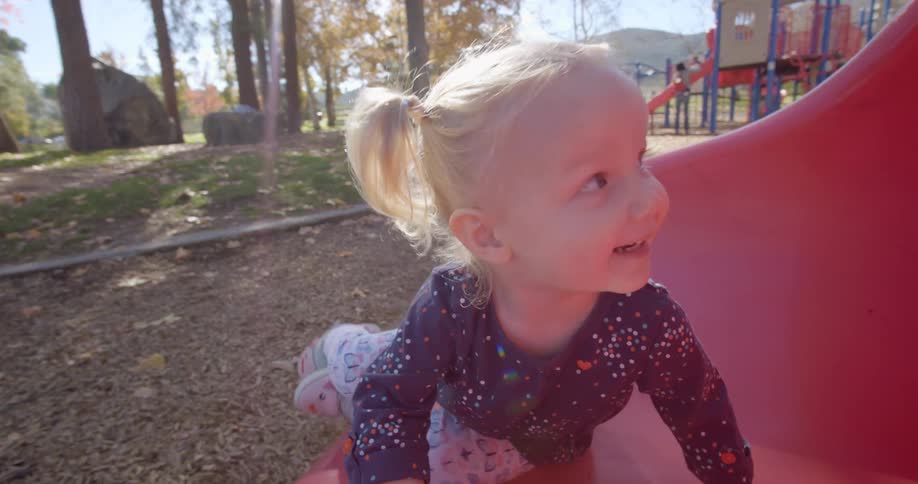 Blonde girl playing in a children playground in a park