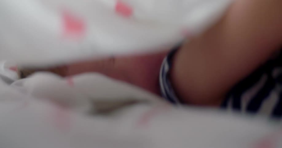 Little girl smiles and laughs while playing under bedsheets