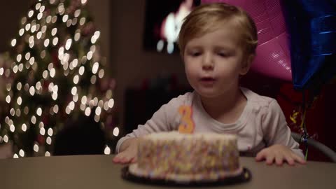 A little boy blows out the candle on his birthday cake and claps