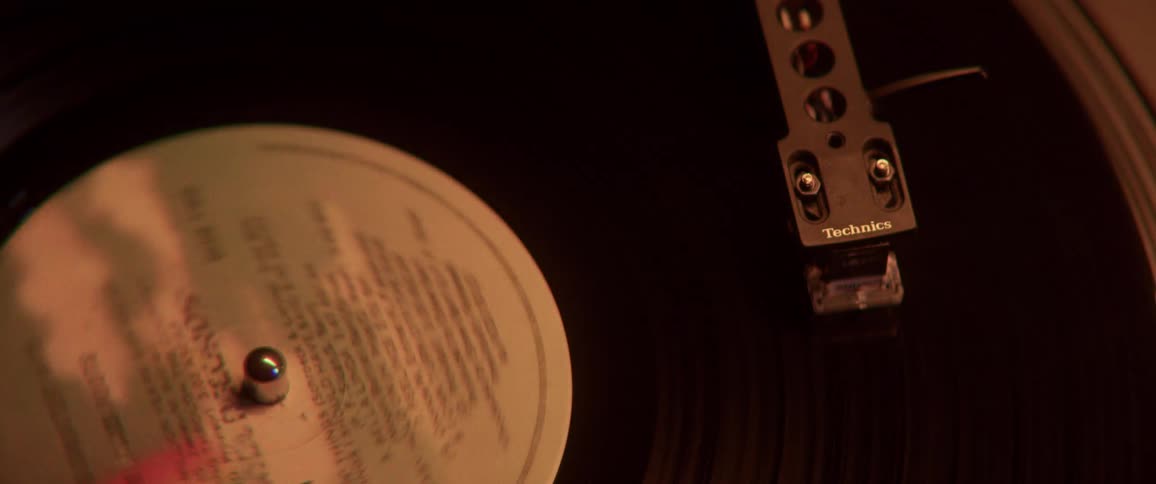 A record spins on a record player in a room with color changing lights