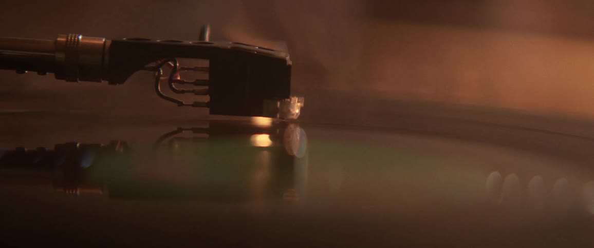 Vinyl record spinning in a turntable under colorful flashing lights and smoke