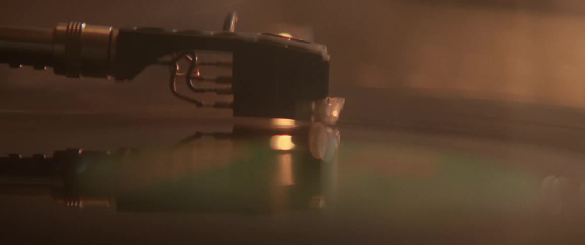 Arm of a record player sits on a record as the record spins