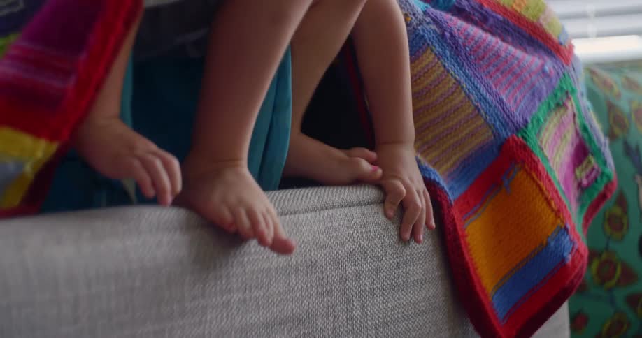 A child stands on the furniture with a sheet cape on his shoulders