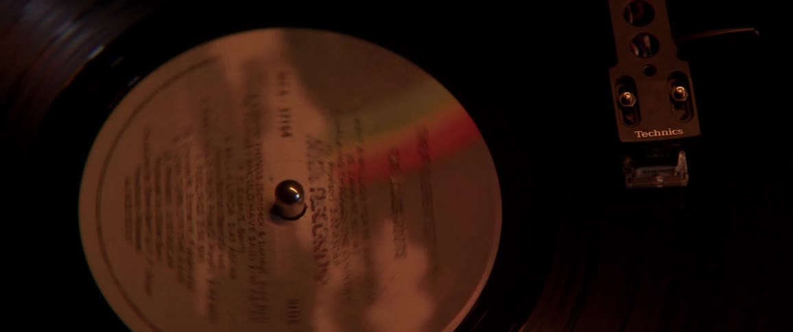 A vinyl record spinning atop a record player in a dimly lit room