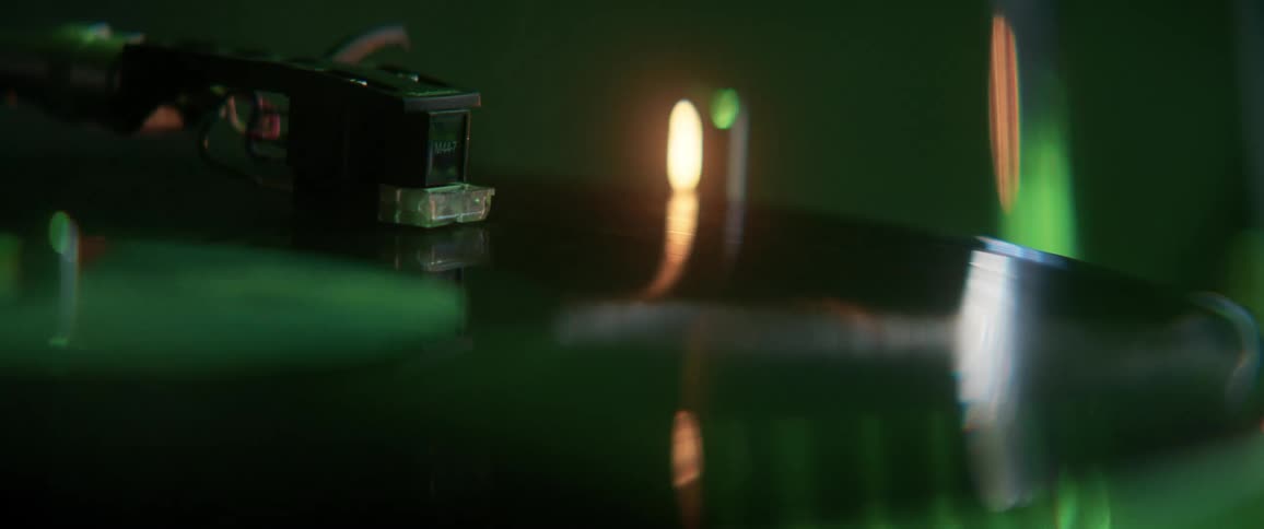 Vinyl record spins in a turntable under colorful lights and smoke