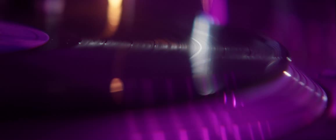 Vinyl record spinning on a turntable under colorful lights and smoke