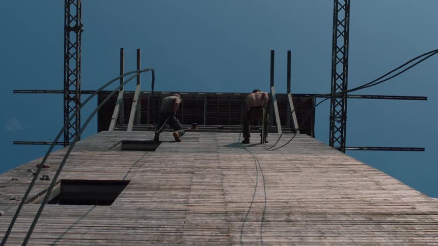 Two men rappel down wall under clear blue sky