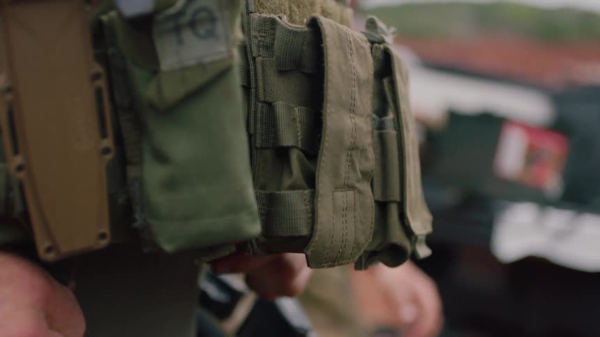 Man buckles tactical vest around waist