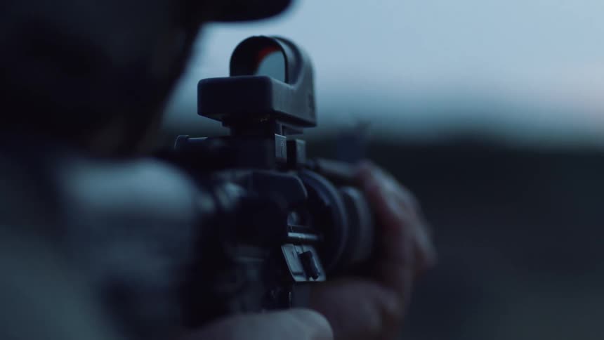 A person holding and shooting a rifle
