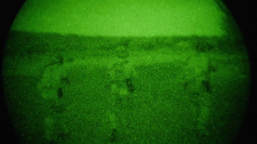 Grainy footage of three soldiers cautiously walking forwards