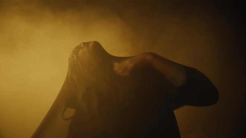 Woman moving under see through fabric in the mist on a dark place