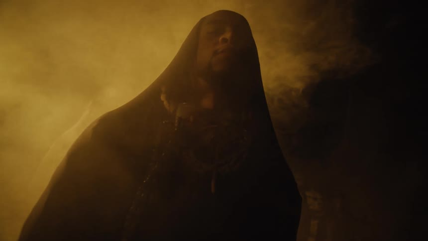 Bearded man wearing a rob standing outdoors at night in the fog